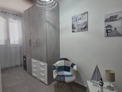a white room with a chair and a cabinet at A Casa di Angela in Capaci