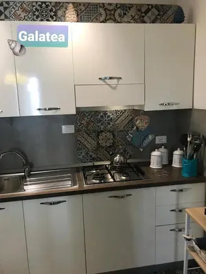 a kitchen with white cabinets and a stove top oven at Casa vacanza galatea San vito lo capo in San Vito lo Capo