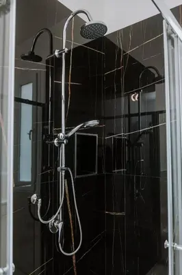 a shower in a bathroom with black tiles at House Paradise- House Arena in Porticello