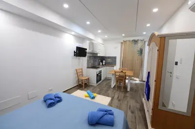 a bedroom with a blue bed and a kitchen at Ummi Taliari in Terrasini