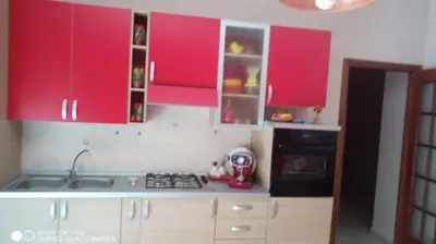 a kitchen with red cabinets and a sink and a stove at Nicitra in Isola delle Femmine