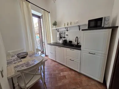 a kitchen with white cabinets and a table with a microwave at A Casa di Iside in Palermo