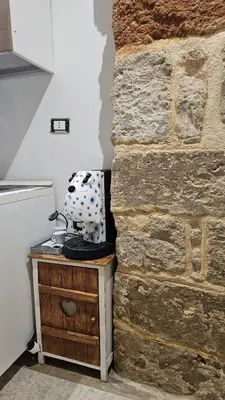 a kitchen with a stone wall next to a table at La Corte Di San Basilio palermo in Palermo