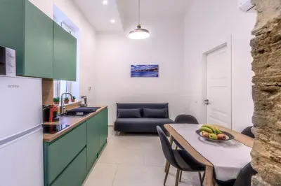 a kitchen with green cabinets and a table with a bowl of fruit at Suites Santa Cecilia in Palermo