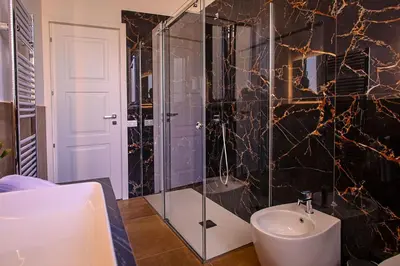 a bathroom with a glass shower and a sink at Suites Santa Cecilia in Palermo