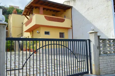 a building with a gate in front of a house at Casa vacanza Onda Lunga in Alcamo