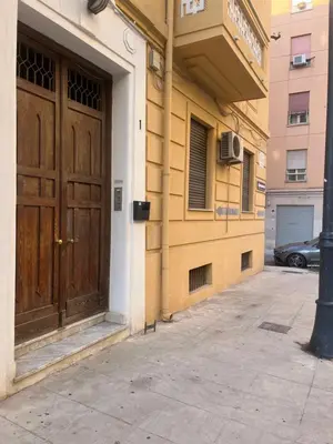 a building with a large wooden door on a sidewalk at Matteo's House in Palermo