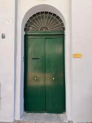 a green door in a white building with an arch at Ai Limoni in Palermo