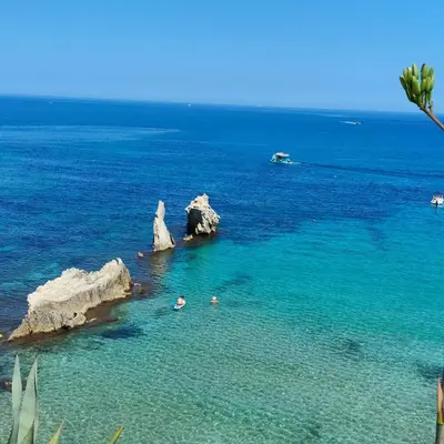 two people swimming in the water near some rocks at Sweet World in Terrasini