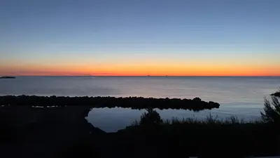 a sunset over the ocean with a reflection in the water at Merlo Holiday Homes Mare in Trabia