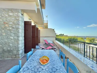 a table on a balcony with a plate of food on it at Merlo Holiday Homes Mare in Trabia
