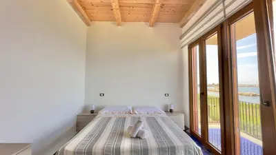 a bedroom with a bed and a large window at Merlo Holiday Homes Mare in Trabia