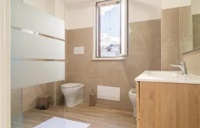 a bathroom with a toilet and a sink and a window at Villa a due passi dal mare in Mandra Capreria