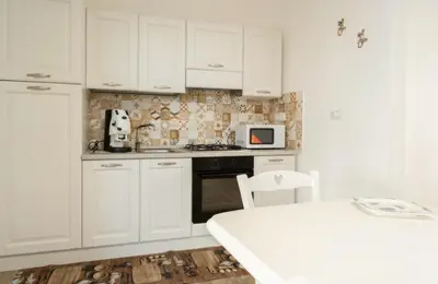 a white kitchen with white cabinets and a white table at Villa a due passi dal mare in Mandra Capreria