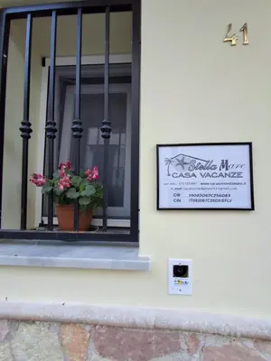 a sign on a building with a window with a flower pot at Stella Mare in Santa Flavia