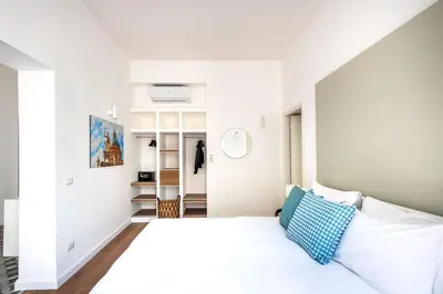 a bedroom with a white bed with a blue pillow at Ci' Capo Apartments by Wonderful Italy in Palermo