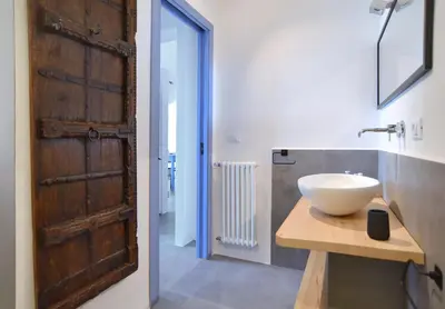 a bathroom with a sink and a wooden door at Re mare exclusive home in Terrasini