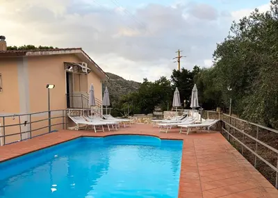 a pool with chairs and umbrellas next to a house at Villa con Piscina in Ventimiglia di Sicilia