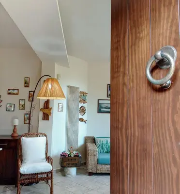 a living room with a wooden door and a chair at Sea View Holiday in Altavilla Milicia