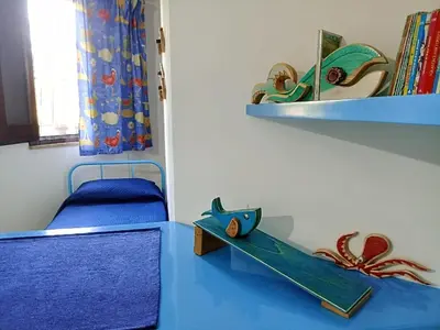 a room with a blue table with a bed and a shelf at Sea View Holiday in Altavilla Milicia