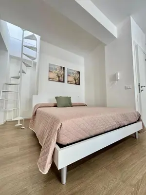 a white bedroom with a bed and a staircase at TerrAmata in Terrasini