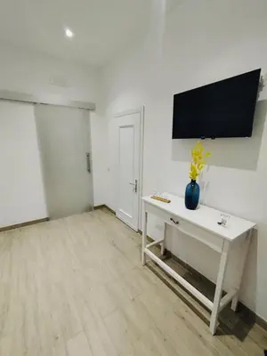a white room with a table and a tv on the wall at D'anthoine apartment in Palermo