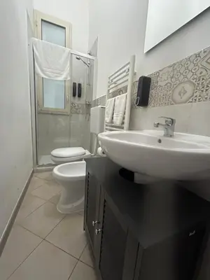 a white bathroom with a sink and a toilet at Florio Rooms in Palermo