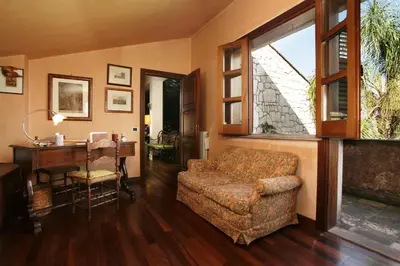 a living room with a couch and a desk and a window at Giardino degli Ulivi in Palermo