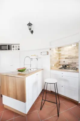 a kitchen with white cabinets and a sink and a stool at Torre Lanza di Guidaloca By DomuSicily in Castellammare del Golfo
