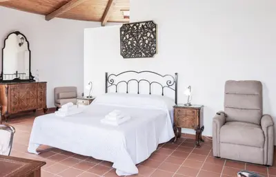 a bedroom with a white bed and a chair at Torre Lanza di Guidaloca By DomuSicily in Castellammare del Golfo