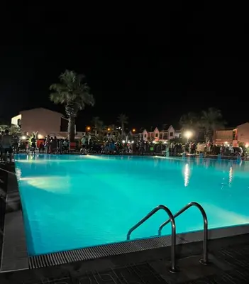 a large swimming pool at night with people standing around it at Casetta mia Seaside in Buonfornello