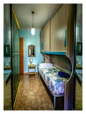 a bedroom with a bed and a table and cabinets at Casetta mia Seaside in Buonfornello