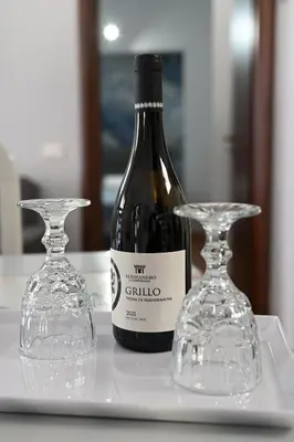 a bottle of wine and two glasses on a table at M&G Holiday House in Terrasini