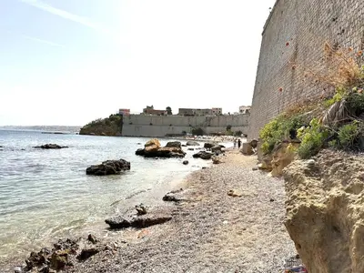 a rocky beach next to the ocean with a building at Fantastic, sea view apartment via Duchessa in Castellammare del Golfo