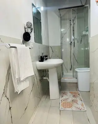 a white bathroom with a sink and a shower at Shamà rooms in Palermo