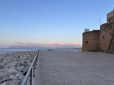 a stone walkway next to the ocean next to a castle at Fantastic sea view Via Duchessa in Castellammare del Golfo