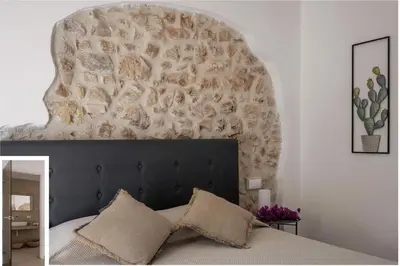 a bedroom with a bed with a stone wall at Historic Villa Overlooking Scopello Sea Stacks in Castellammare del Golfo