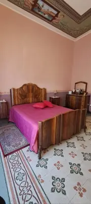 a bedroom with a wooden bed with a pink blanket at Casa Mazzini in Carini