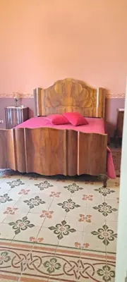 a bedroom with a wooden bed with pink sheets at Casa Mazzini in Carini