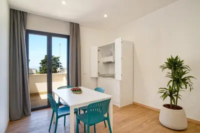 a dining room with a table and chairs and a plant at Ella Suites Apartments in Terrasini