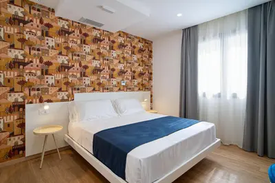 a bedroom with a large bed and a wall of pictures at Ella Suites Apartments in Terrasini