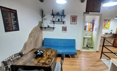 a room with a table and a blue couch at Roccaforte House - Palermo in Palermo