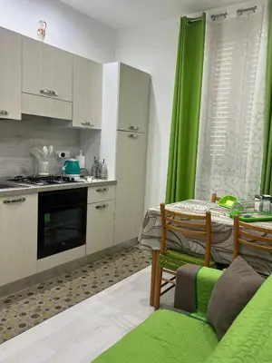 a kitchen with green curtains and a table and chairs at Angela apartments in Partinico