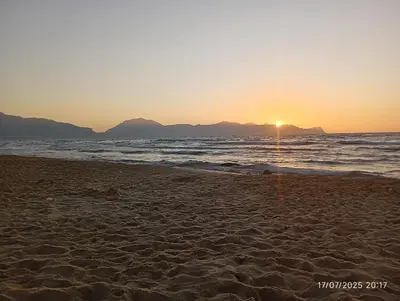 a beach with the sun setting over the ocean at MuSa Apartament in Balestrate