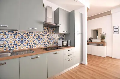 a kitchen with white cabinets and a tile wall at iFlat Papi living in Palermo