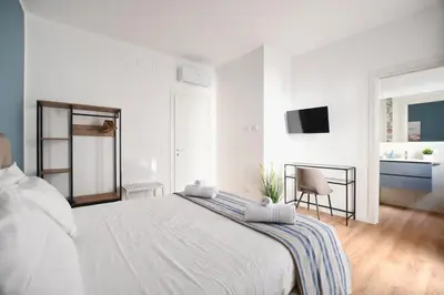 a white bedroom with a large bed and a chair at iFlat Papi living in Palermo