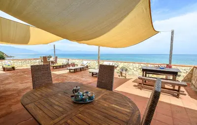 a wooden table and chairs with an umbrella and the ocean at Beach Front Apartment In Trappeto in Trappeto