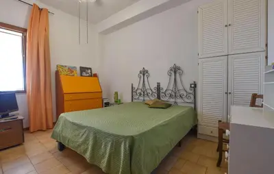a bedroom with a bed with a green bedspread and a dresser at Beach Front Apartment In Trappeto in Trappeto