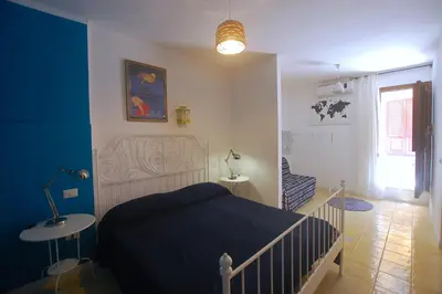 a bedroom with a bed and a table and a window at Appartamento Bouganville in Castellammare del Golfo