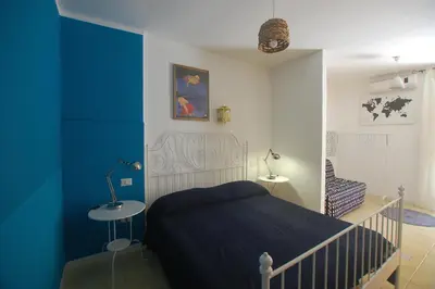 a bedroom with a bed and a blue wall at Appartamento Bouganville in Castellammare del Golfo